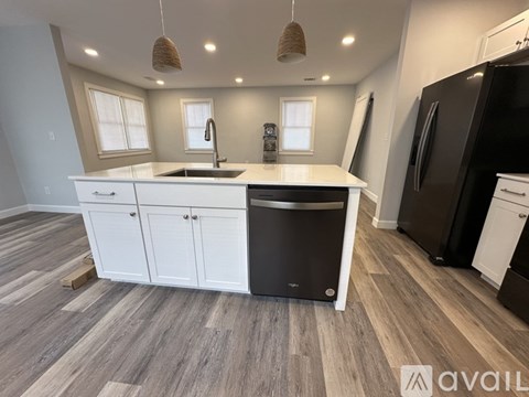 A kitchen with a black dishwasher and white cabinets.
