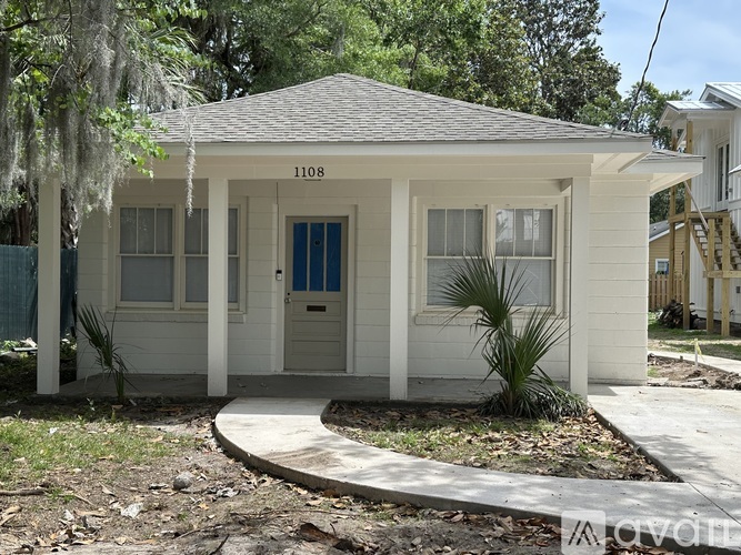 A small white house with a blue door and a porch.