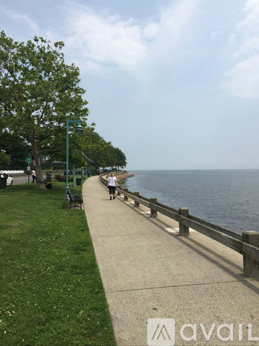 A person is walking on a sidewalk next to a body of water.