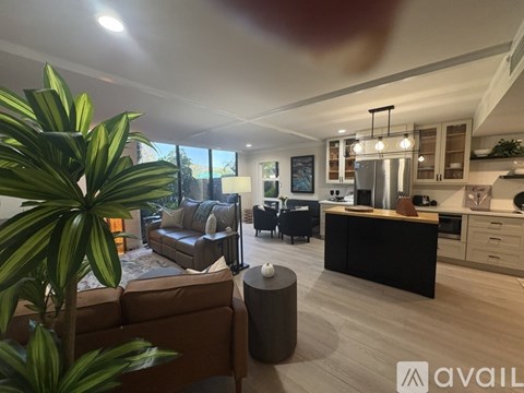 A modern living room with a brown sofa and a large window.