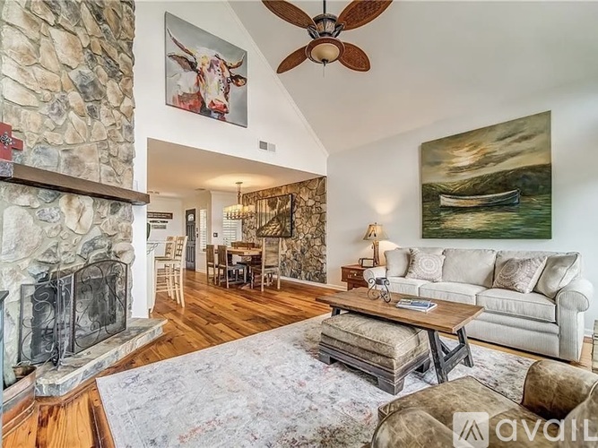 A living room with a stone fireplace and a painting of a boat on the wall.