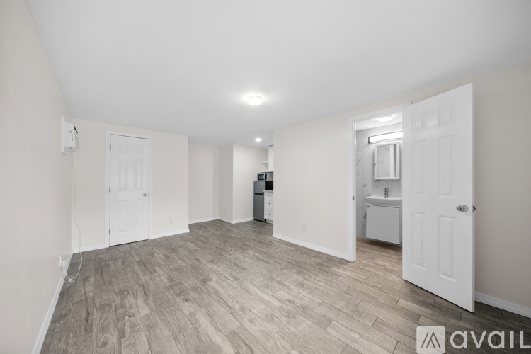 A spacious room with light wood flooring and white walls.