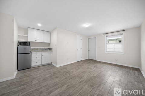 A spacious kitchen with white cabinets and a grey floor.