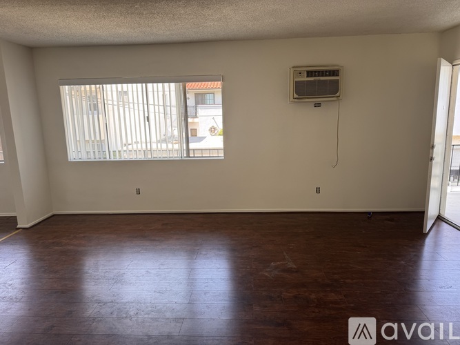 A room with a window and a wall-mounted air conditioning unit.