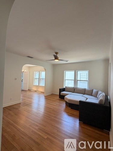 A spacious living room with a large couch and a ceiling fan.