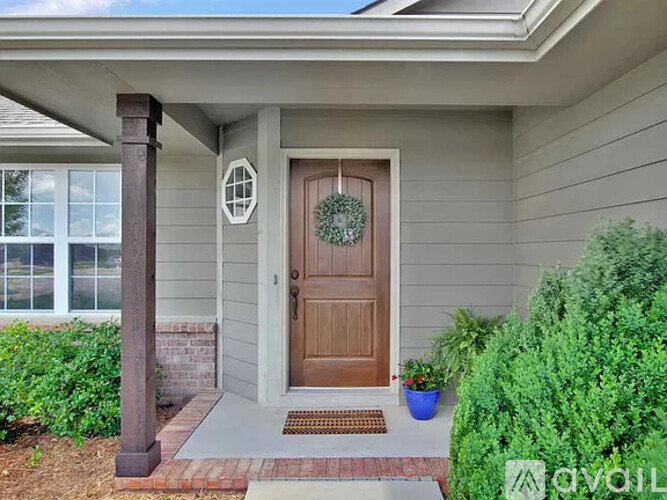 A house entrance with a brown door and a wreath on it.