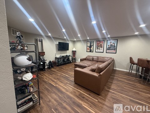 A living room with a brown couch and a television on the wall.