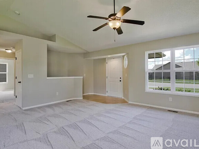 A spacious room with a ceiling fan and a large window.