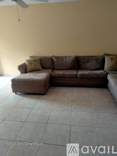 A brown couch with a pillow is in the middle of a room.