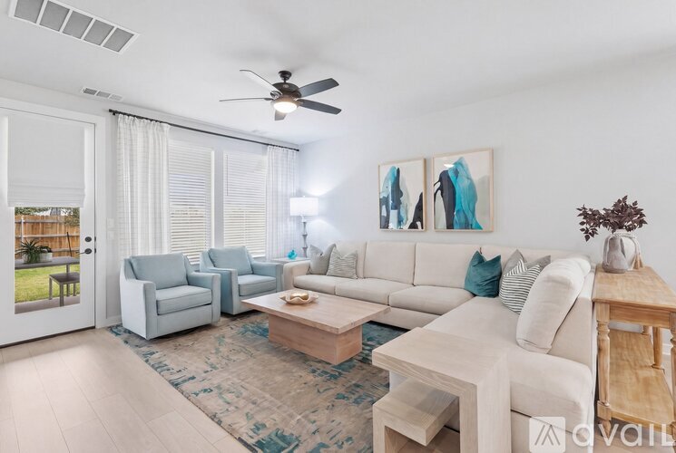 A living room with a white couch, a grey armchair, a coffee table, and a painting on the wall.