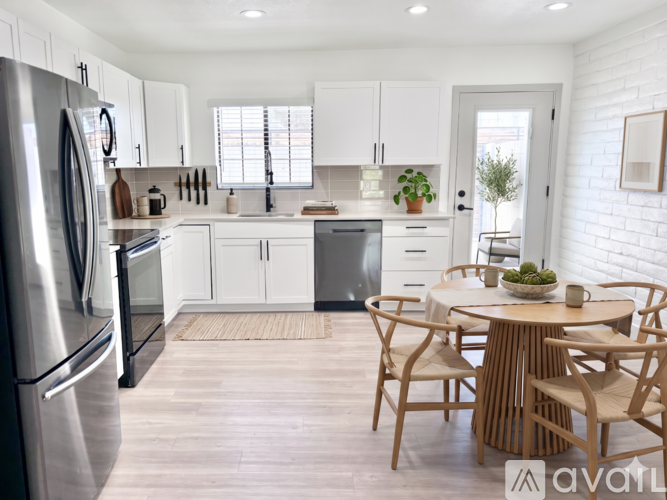 A kitchen with a refrigerator on the left and a dining table with chairs in the middle.