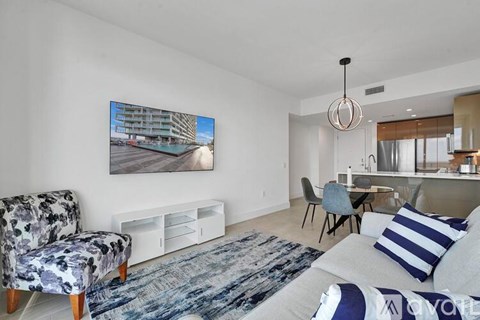 A modern living room with a large painting on the wall and a grey sofa with blue and white striped pillows.