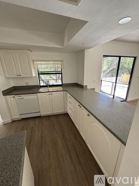 A kitchen with white cabinets and a grey countertop.