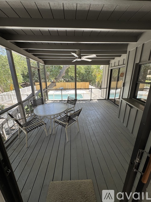 A patio with a table and chairs overlooking a pool.