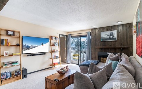 A living room with a large couch and a flat screen TV mounted on the wall.