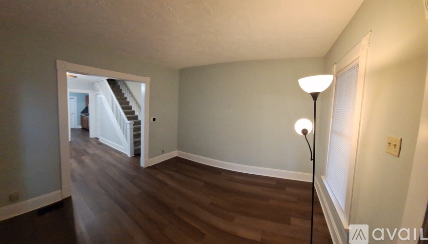 A room with wooden floors and a lamp on the floor.
