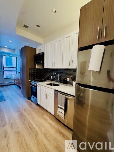 A kitchen with wooden cabinets and a stainless steel refrigerator.