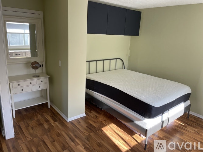 A bedroom with a bed, desk, and window.