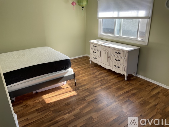 A bedroom with a bed, dresser, and window.