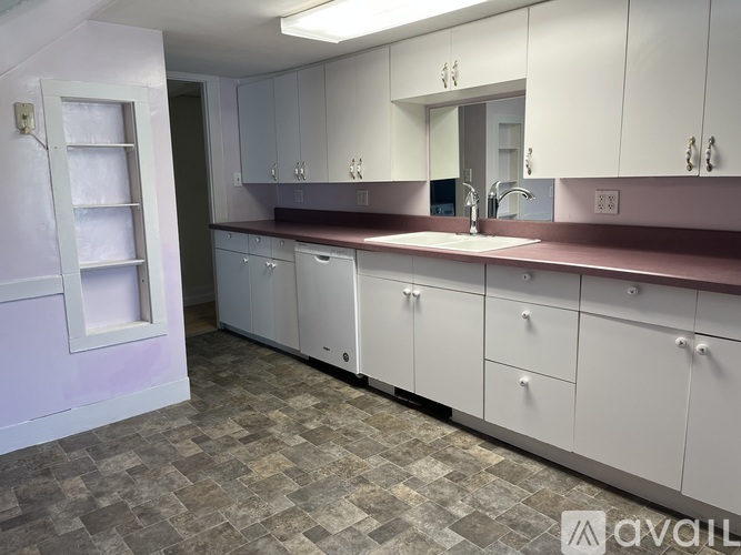 A kitchen with white cabinets and a maroon backsplash.
