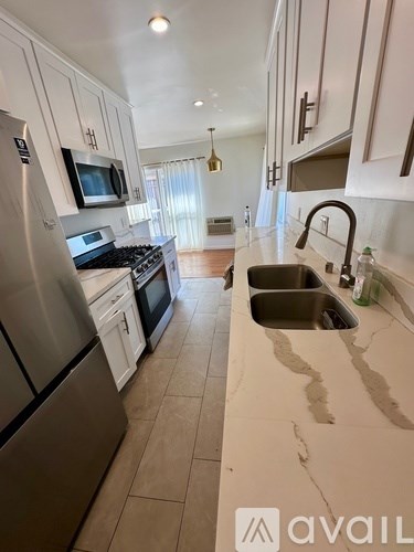 A kitchen with a stainless steel refrigerator and a marble countertop.