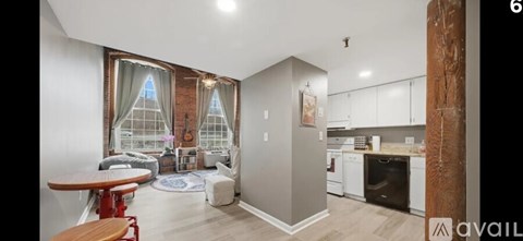 A living room with a dining table and a kitchen area in the background.
