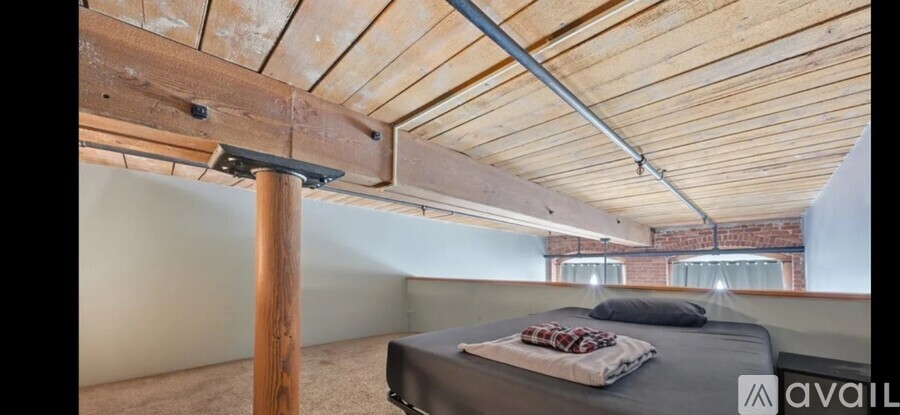 A bedroom with a bed and a wooden beam on the ceiling.