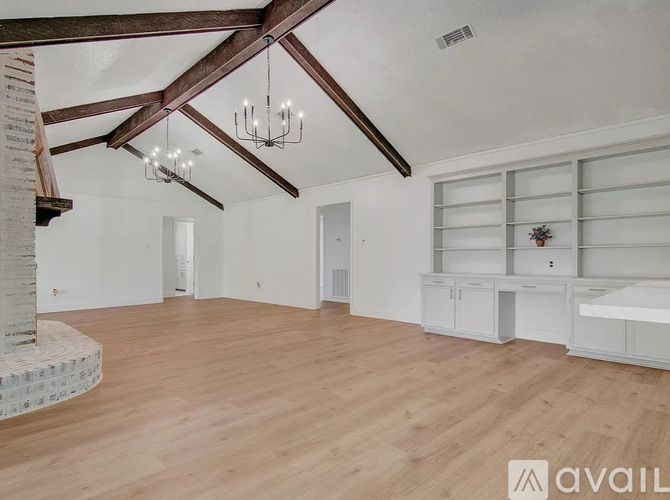 A spacious room with wooden floors and a chandelier.
