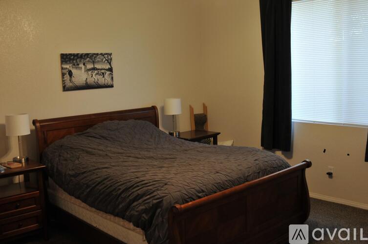 A bedroom with a large bed and two lamps on the nightstands.