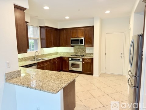 A kitchen with granite countertops and wooden cabinets.