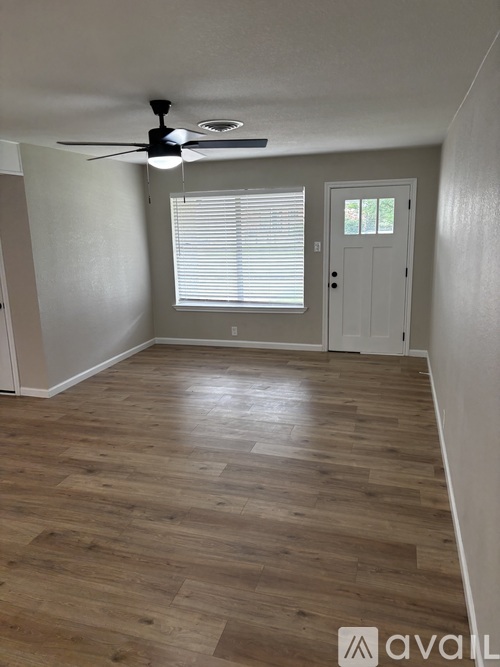 A room with a ceiling fan and wooden flooring.