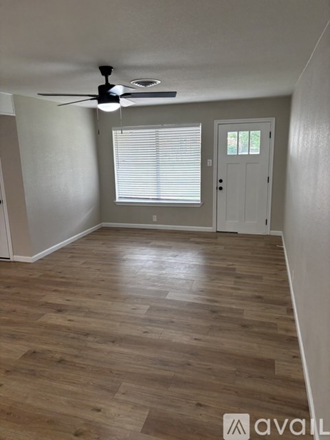 A room with a ceiling fan and wooden flooring.