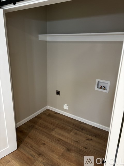 A small, empty room with wooden floors and white walls.