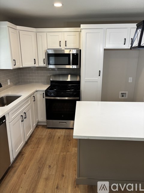 A kitchen with white cabinets and a wooden floor.
