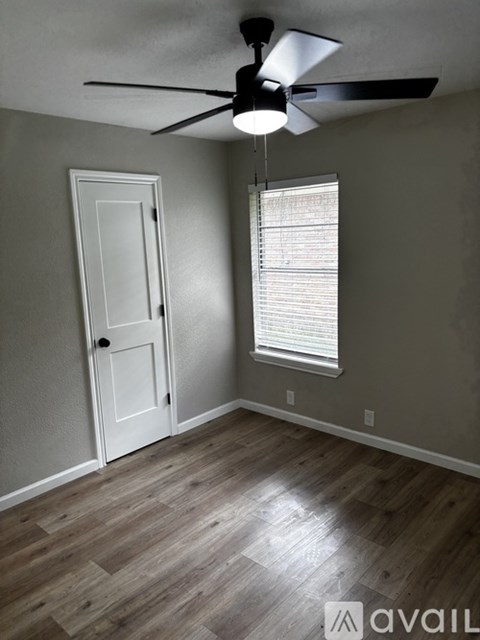 A room with a ceiling fan and a door.