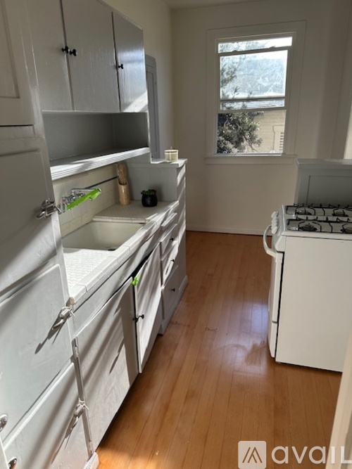 A small kitchen with white appliances and wooden floors.