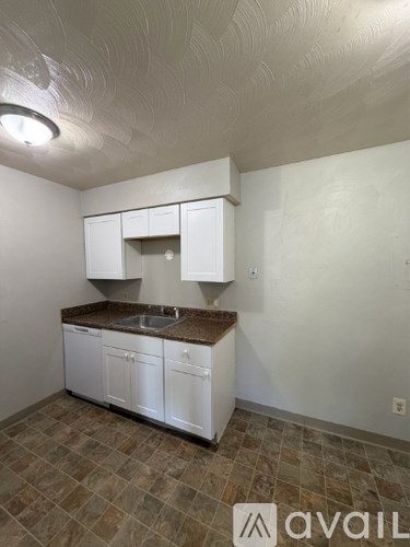 A kitchen with white cabinets and a brown countertop.