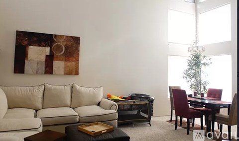 A living room with a white couch, a coffee table, and a painting on the wall.