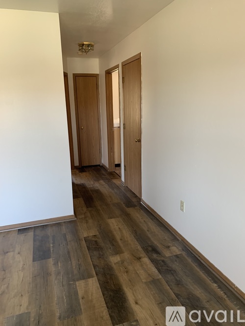 A hallway with wood floors and two doors.