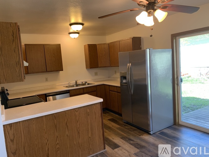A kitchen with wooden cabinets and a stainless steel refrigerator.