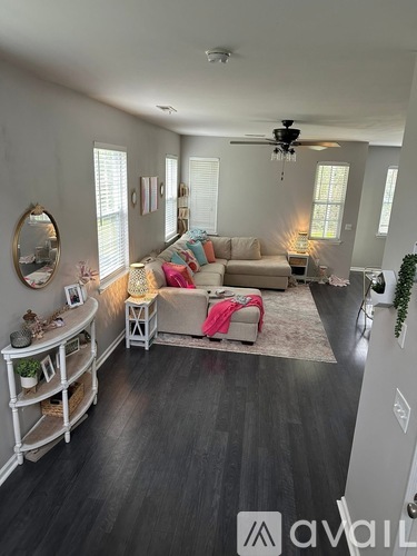 A living room with a couch, a round mirror, and a ceiling fan.