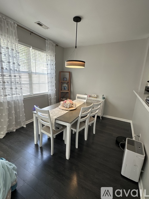 A dining room with a table set for four and a white chair.