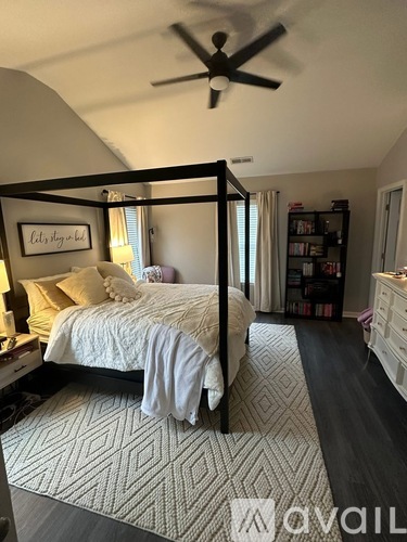 A bedroom with a four poster bed and a ceiling fan.