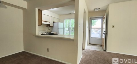 A room with a kitchenette and a door leading to a balcony.