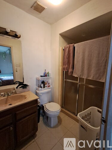 A bathroom with a toilet, sink, and a window with a towel hanging on it.