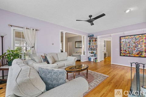 A living room with a white couch, a coffee table, and a painting on the wall.