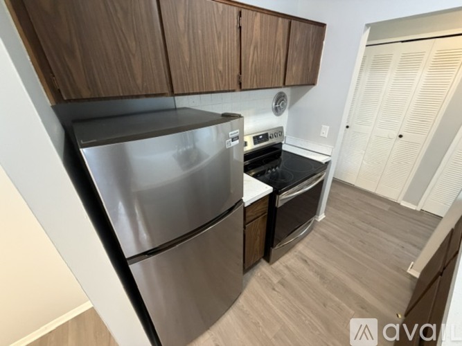 A kitchen with a stainless steel refrigerator and wooden cabinets.