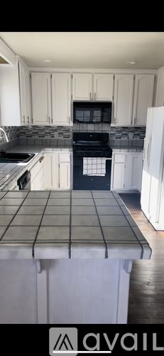 A kitchen with white cabinets and a black stove top oven.