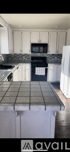 A kitchen with white cabinets and a black stove top oven.