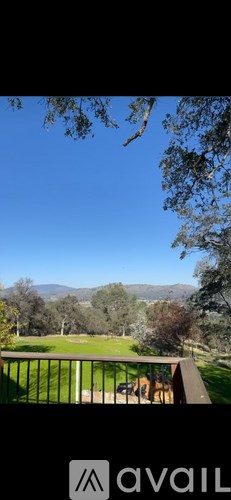 A balcony overlooks a lush green lawn and distant mountains.